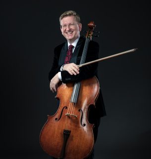Man with cello in front of a black background